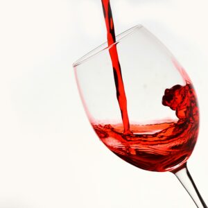 Elegant shot of red wine being poured into a tilting glass against a white background.