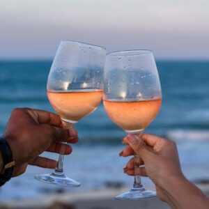 Couple toasts with rose wine by the seaside in Aquiraz, Brasil.