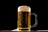 A detailed shot of a cold beer glass with frothy top against a black background.